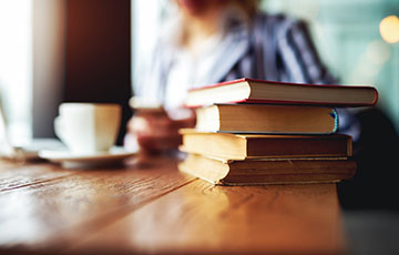 Woman with books, a mug, laptop and cell phone