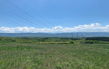 Power lines crossing through a field with clouds in the sky